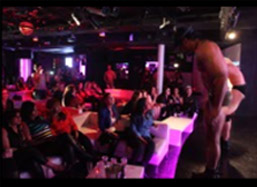 Male stripper on stage in front of a huge crowd.