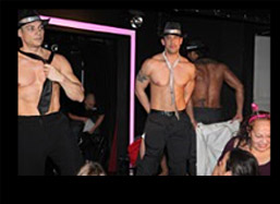 Male strippers on stage at the male strip club taking off all of their clothes for a bachelorette party in NYC.